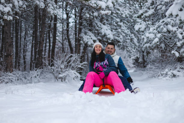 istock Beautiful young and romantic couple sledding and having fun in the snow while wearing colorful outfits 1365497061