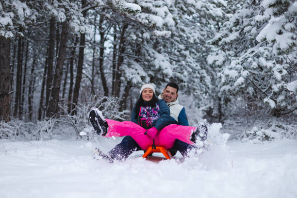 istock Beautiful young and romantic couple sledding and having fun in the snow while wearing colorful outfits 1365497063