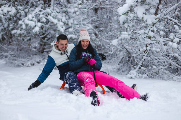 istock Beautiful young and romantic couple sledding and having fun in the snow while wearing colorful outfits 1365497065
