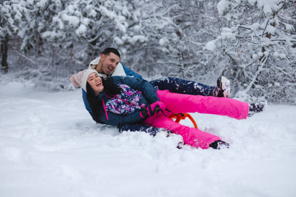 istock Beautiful young and romantic couple sledding and having fun in the snow while wearing colorful outfits 1365497067