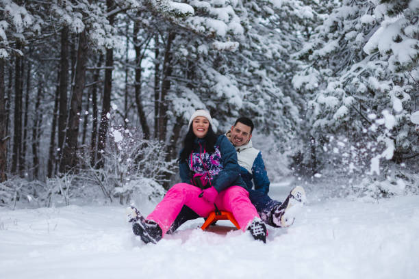 istock Beautiful young and romantic couple sledding and having fun in the snow while wearing colorful outfits 1365497715