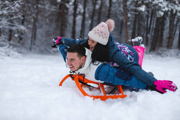 istock Young beautiful and romantic couple having fun in the snow while laying on a sled 1365497718