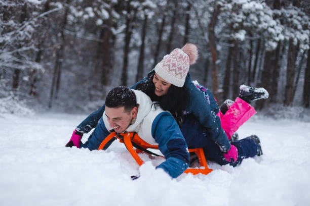 istock Young beautiful and romantic couple having fun in the snow while laying on a sled 1365497726