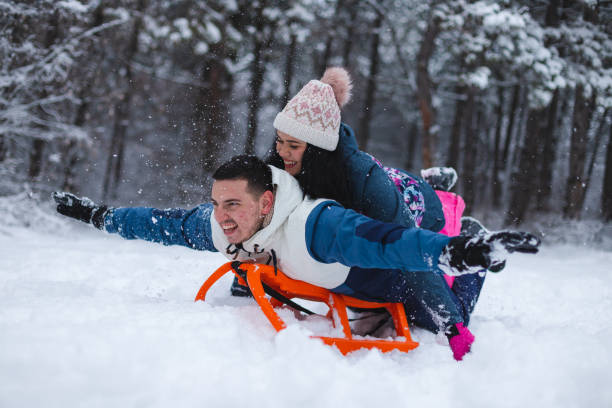 istock Young beautiful and romantic couple having fun in the snow while laying on a sled 1365497727