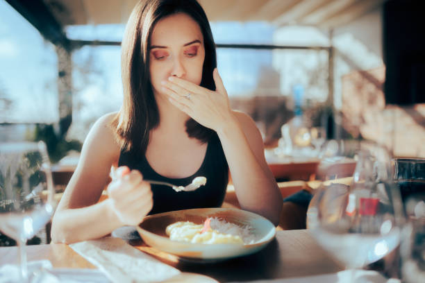 Restaurant Customer Eating her Meal Feeling Sick Woman suffering after having an altered unproperly cooked meal food poisoning stock pictures, royalty-free photos & images