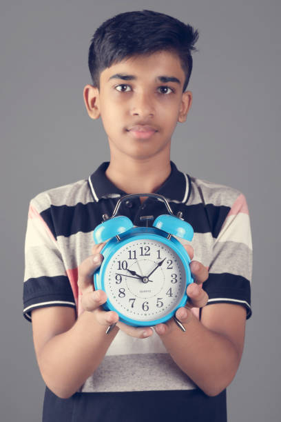istock Indian boy holding Alarm Clock 1365509429