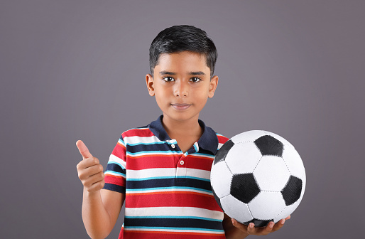 Indian school boy holding a football with Thumbs up