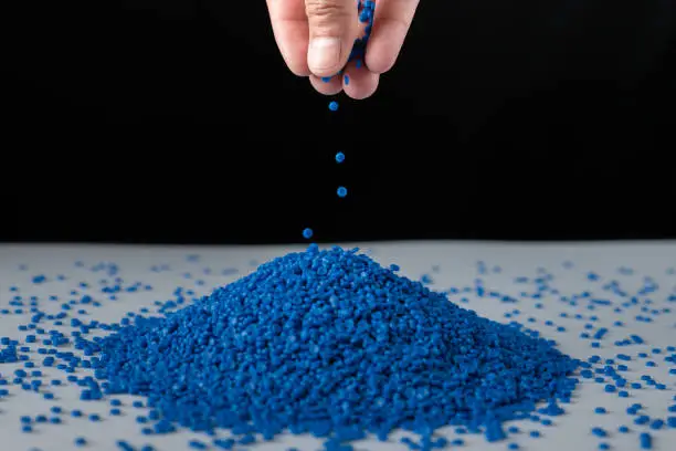 Photo of Blue plastic beads on wood  background, Polymers bead or polymer resin, polymer pallet, Product from petrochemical plants. granules polymer, Concept roof of house is made of polymer plastic.