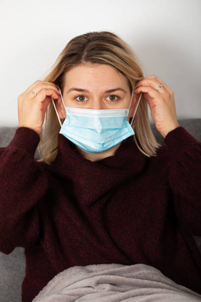 istock Sick woman with protective mask at home 1365512842