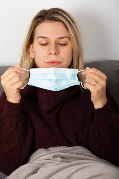 istock Sick woman with protective mask at home 1365512869