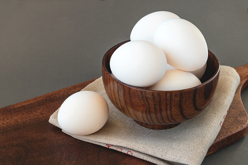 Fresh healthy diet eggs in a wooden bowl on a cutting board.
