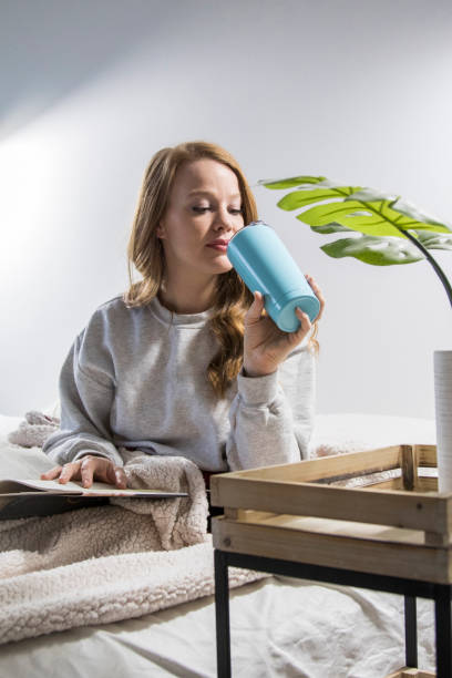 Woman drinks from a water bottle in her bed stock photo