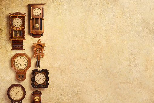 Several old clocks hang on a richly textured wall that provides ample room for copy or text.
