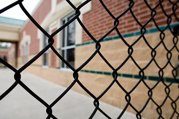 Chain link fencing alongside a brick school building.
