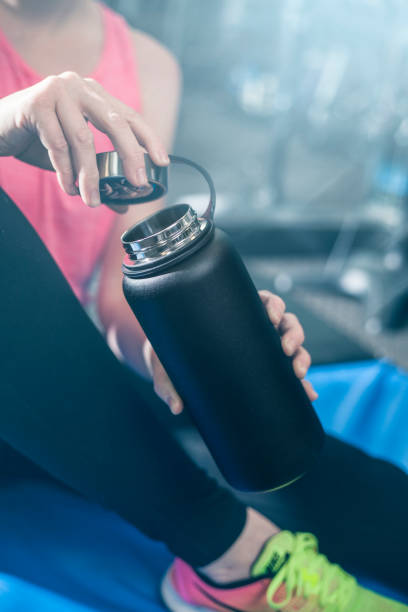 istock A woman opens a black water bottle in a gym 1365516280