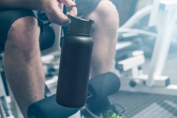 istock Man holds black water bottle in gym 1365516352