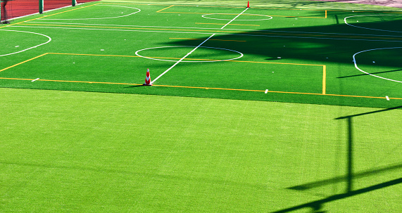 High angle view of white and yellow line marking on the artificial green grass sports field.