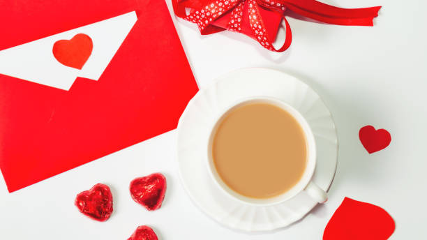 istock Valentine's day composition with coffee cup and box of chocolate hearts and envelope with blank note mockup inside on white background. Space for text. Love and Valentine's Day concept. 1365526407