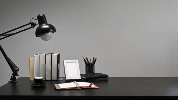 istock Empty picture frame, books, pencil holder and lamp on black table. 1365527098