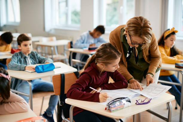 uczennica ucząca się z pomocą nauczyciela podczas zajęć w szkole podstawowej. - elementary school building zdjęcia i obrazy z banku zdjęć