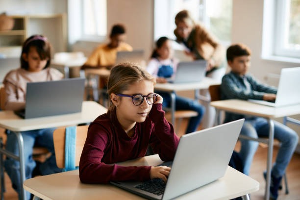 istock Little girl e-learning on laptop in the classroom at school. 1365527867