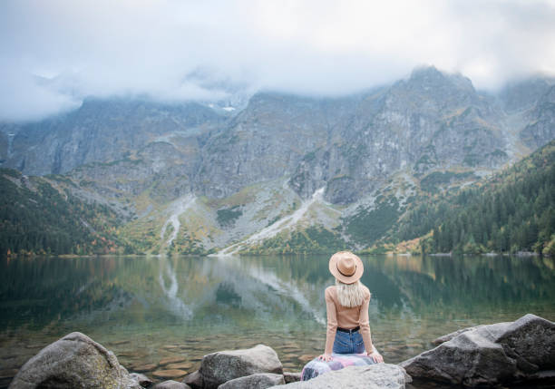 istock Young woman on a hiking trip sitting on a rock 1365532081