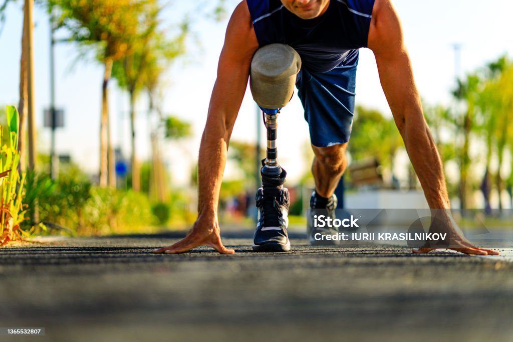 disabled athlete man with prosthetic leg starting to run at the beach on a treadmill outdoors at sunset disabled athlete man with prosthetic leg starting to run at the beach on a treadmill outdoors at sunset. Athlete with Disabilities Stock Photo