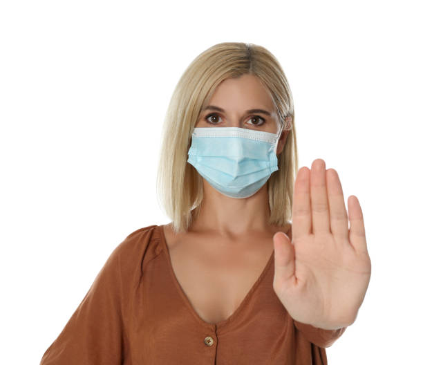 istock Woman in protective mask showing stop gesture on white background. Prevent spreading of coronavirus 1365532832