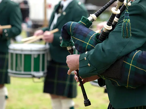 A piper playing bagpipes at a Highland Games event in Scotland