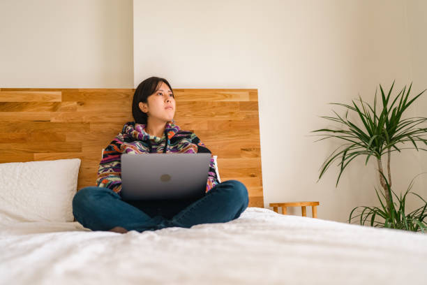 istock Young woman relaxing on bed in bedroom 1365539146