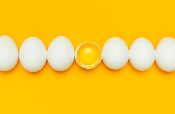 istock White chicken eggs and one broken egg with yolk on yellow background top view flat lay copy space. Creative food minimalistic background, Easter. Natural healthy food and organic farming concept. 1365539580