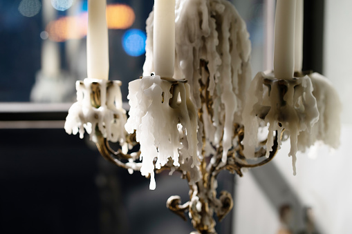 Photo of white wax dripping from candles on a candlestick.