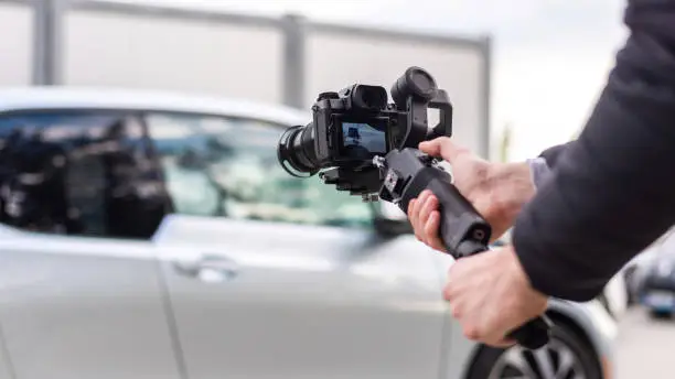 Camera man with stabilizer shooting parked BMW i3