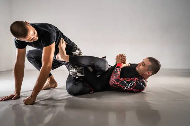 Brazilian jiu jistu bjj no-gi grappling training two male athletes drilling technique or sparring at gym academy leg attack heel hook position submission