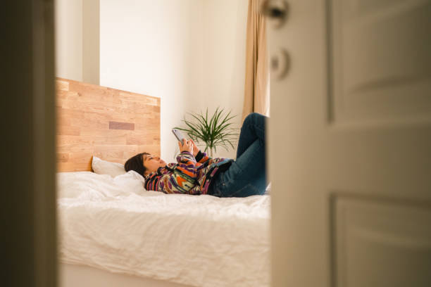 istock Young woman relaxing on bed in bedroom 1365540754