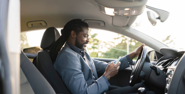 istock afro american man in car interior while looking at his mobile phone 1365541822