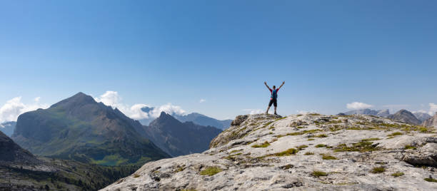 istock Hiker raising his arms in front of a panoramic mountain view 1365542491