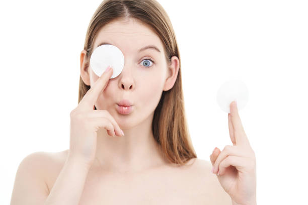 Young woman indulges with cotton pads and makes funny face expression. stock photo