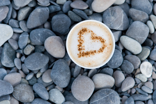 Cappuccino cup with heart on the beach