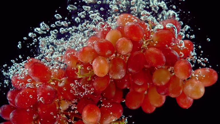 SLO MO LD Cluster of red grapes falling into water