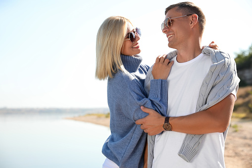 Happy couple in stylish sweaters on beach