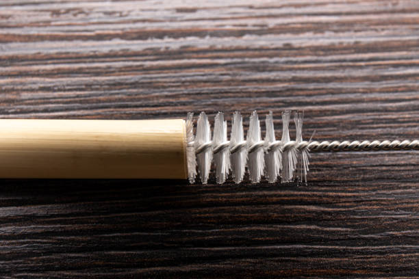 istock Close up view of using drinking straw cleaner brush to clean reusable bamboo drinking straw, indoors at home. 1365553260
