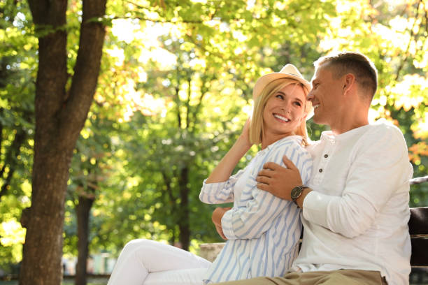 istock Happy couple sitting on bench in summer park 1365553281
