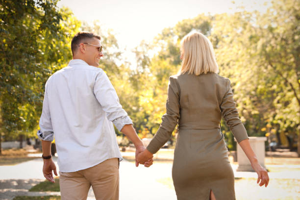 istock Happy couple walking along park on summer day 1365553282