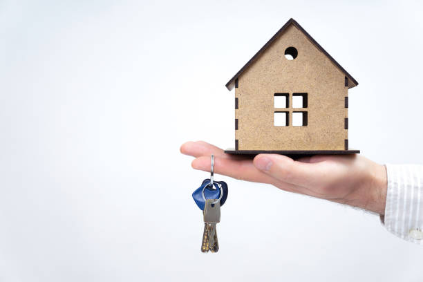 istock Male hand holding a house model and keys isolated 1365555497