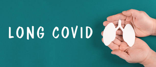 The words long covid are standing on a paper, hands hold a lung, breathing problems after Covid-19 disease stock photo