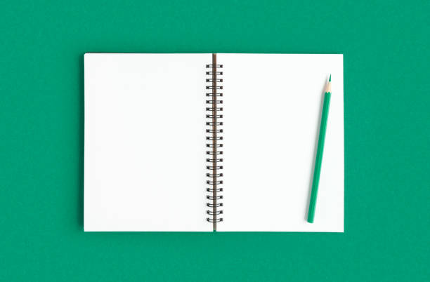 Notebook with pencil. Open notebook on dark green color background, spiral notepad on table. Top view of open notepad with blank pages, office flat lay. White Page for your write. Copy Space