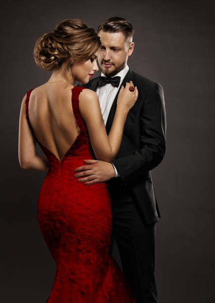 mode hochzeitspaar verliebt. beauty-frau im sexy kleid mit nacktem rücken und gutaussehender mann im schwarzen anzug. elegante herren und lady über dunkelgrauem hintergrund - couple men fashion luxury stock-fotos und bilder