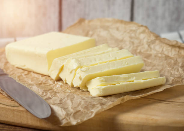istock Fresh butter block sliced on wooden cutting board on rustic background 1365562443