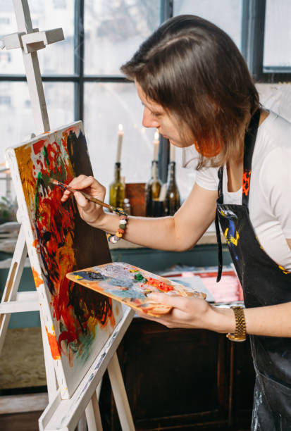 istock Woman artist creating canvas with paint in studio 1365562700